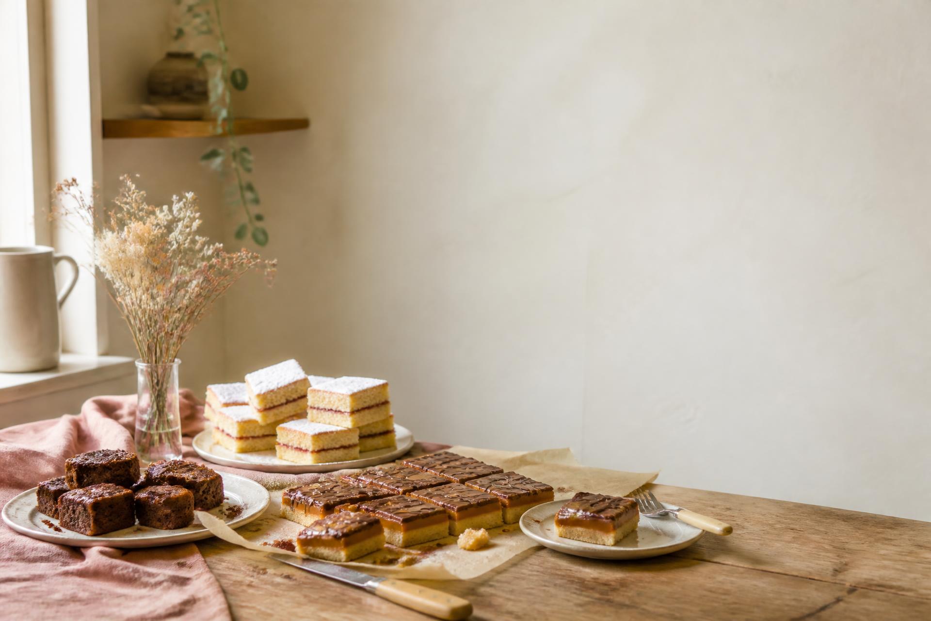 A table of homemade traybakes and cake slices in a cosy kitchen
